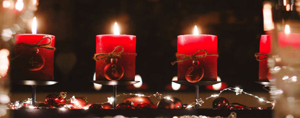 4 rote Adventskerzen auf dunklem Hintergrund