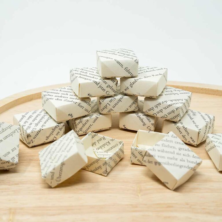 Kleine Origami Geschenkbox mit Deckel auf Holztablett gestapelt
