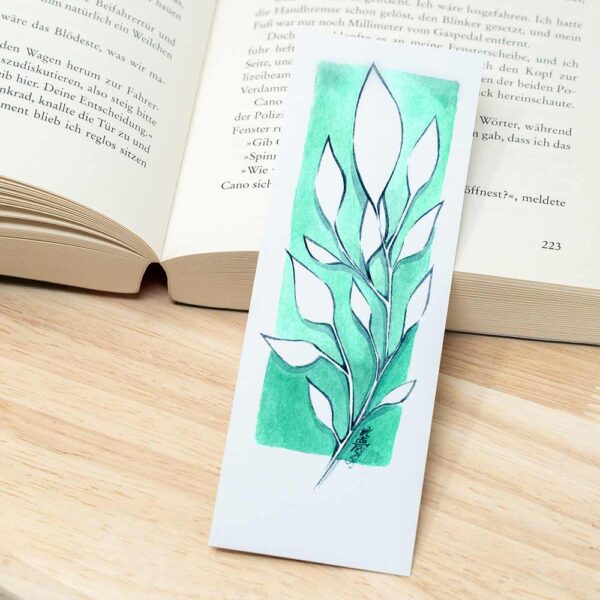 Lesezeichen mit Blumen neben Buch
