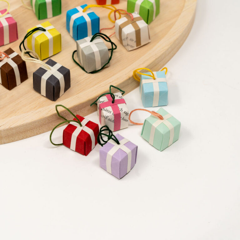 Mehrere kleine mini Origami Geschenkboxen vor einem Holztablett