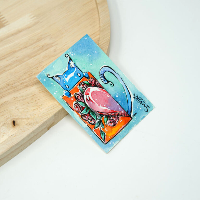 Handgezeichnete ACEO Karte mit blauem Kater Pumpkin der eine orange Karte mit halbem Herz und Rosen hochhält vor türkis-blauem Aquarellhintergrund mit weißen Lichtpunkten.