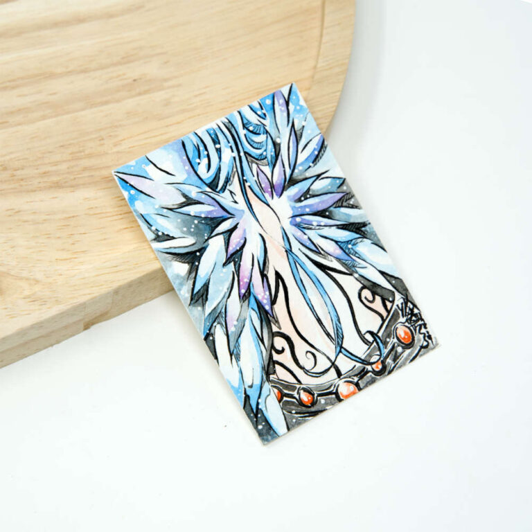 Handgezeichnete ACEO Karte mit ausgebreiteten Engelsflügeln in Eisblau und Lila, mit filigranem Metallschmuck und roten Edelsteinen im unteren Bildbereich.