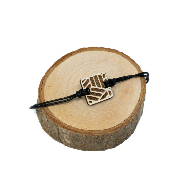 Verstellbares schwarzes Kordel-Armband mit quadratischem Holzanhänger und lasergravierten japanischem Würfelmuster aus ineinandergreifenden Rauten und Diagonalen auf hellem naturbelassenem Holzhintergrund.