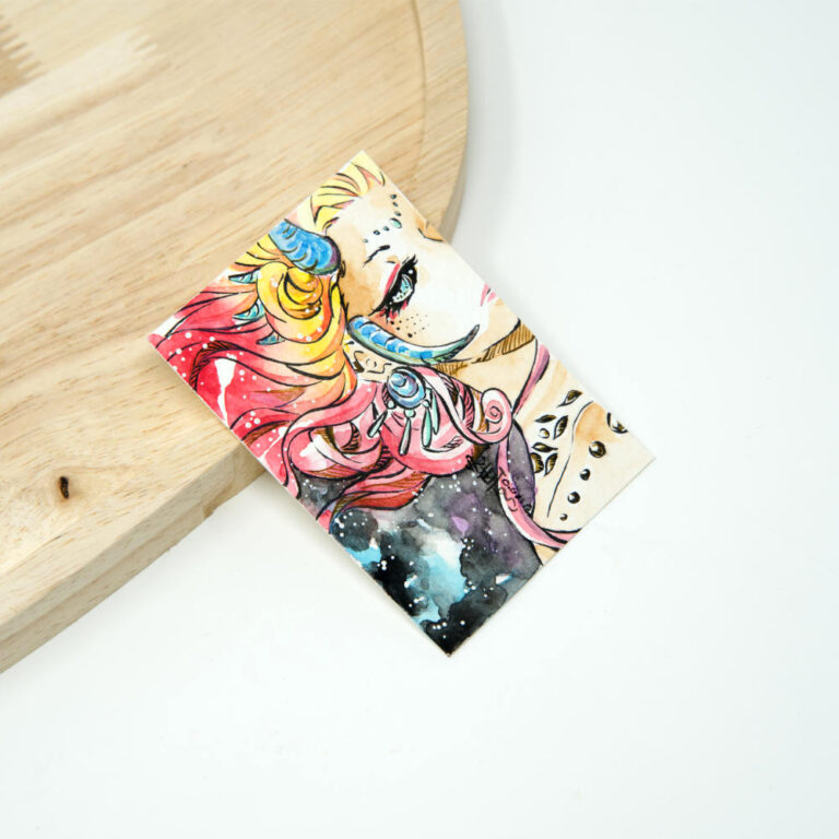 Handgezeichnete ACEO Karte mit gehörnter Dämonin, fließendem rotem und pinkem Haar, blauen und goldenen Hörnern vor dunklem schwarzem und lila Aquarellhintergrund.