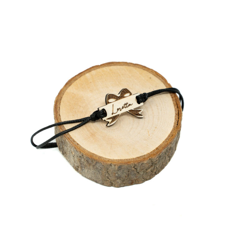 Verstellbares schwarzes Kordel-Armband mit lasergeschnittenem Holzanhänger in Schleifenform und graviertem Wunschnamen Loretta auf hellem naturbelassenem Holz.