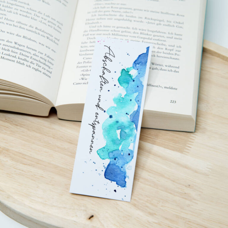 Aquarell-Lesezeichen mit abstraktem blauem Aquarellhintergrund und dem seitlichen Spruch Abschalten und Entspannen in eleganter Schrift auf Papier.